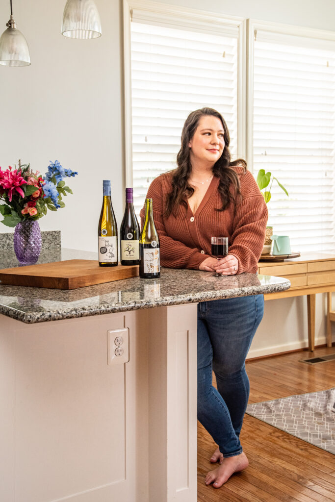 brunette holding a glass of red wine standing in a kitchen