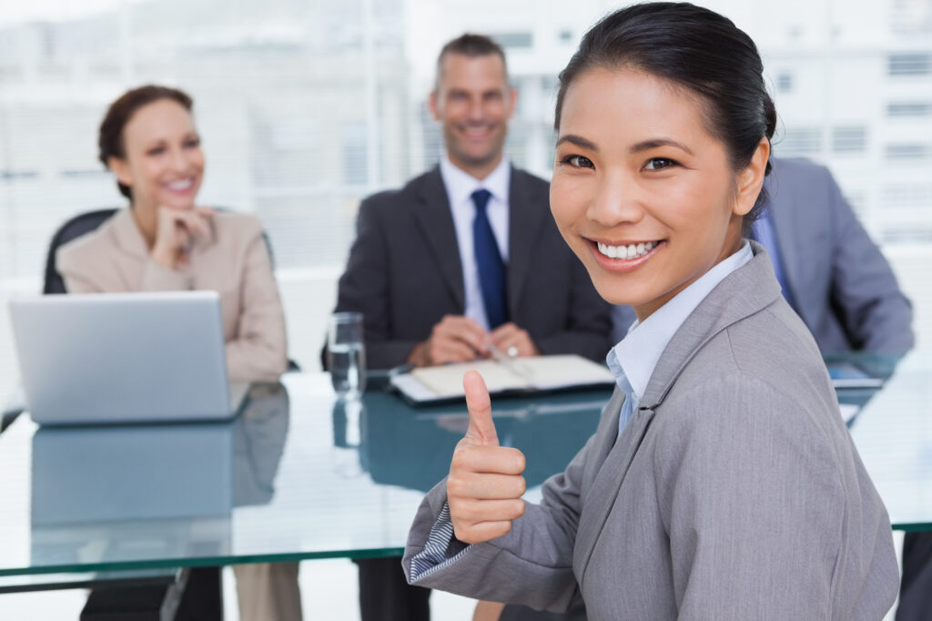 Young applicant in bright office giving thumb up after obtaining the job