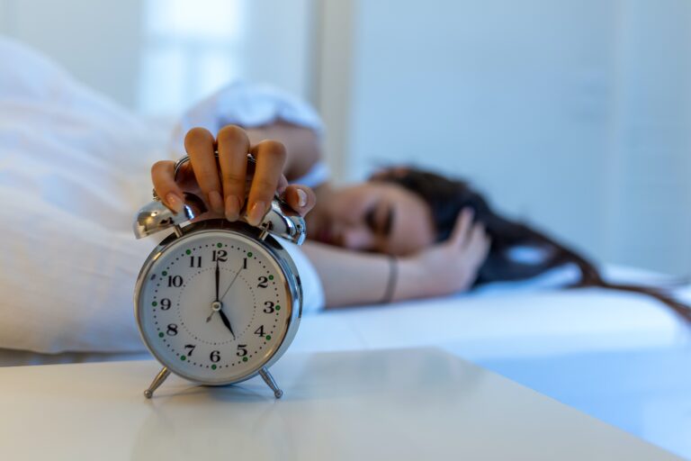 woman turning off an alarm clock