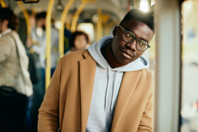 Positive Affirmations for Eco-Anxiety - man stands on a public transport leaning up a window looking sad