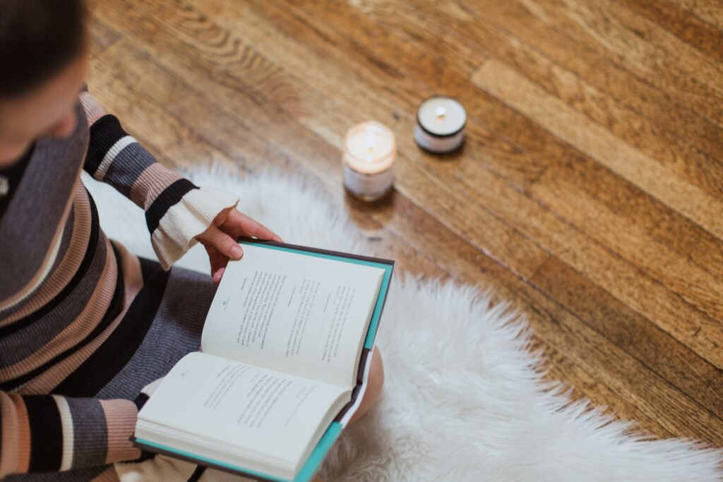 Woman reading a book with candles in the background
