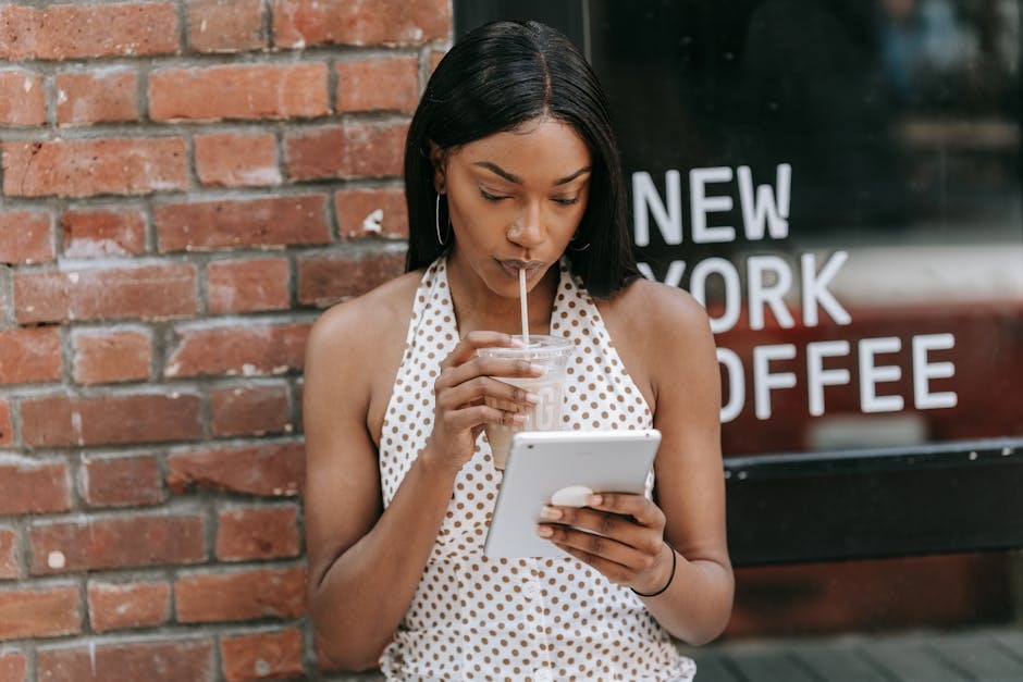 Young woman in a stylish romper working on a laptop at a city coffee shop