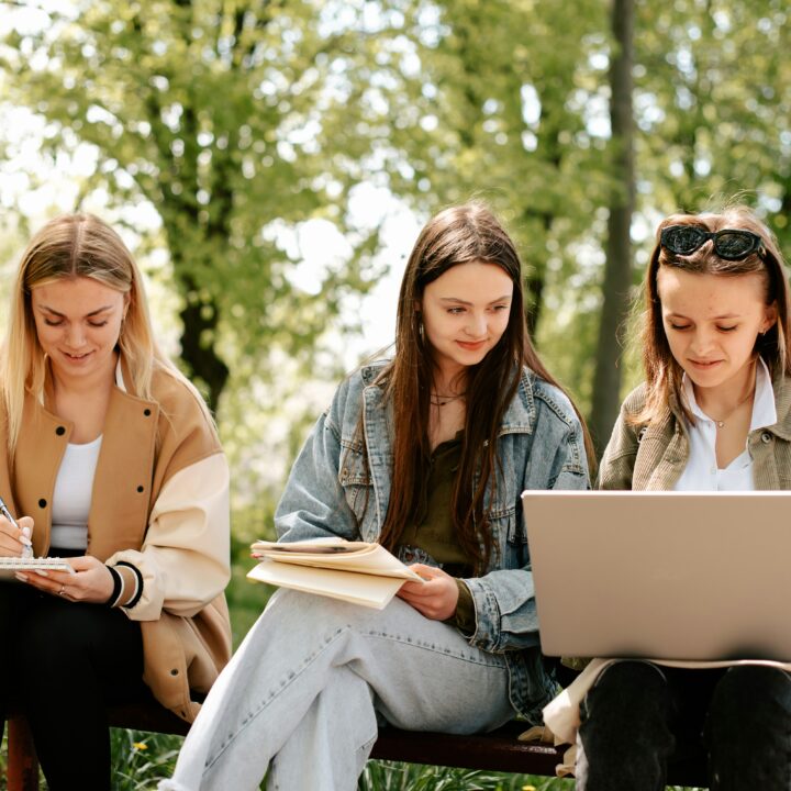 three college girls studying outside on a computer