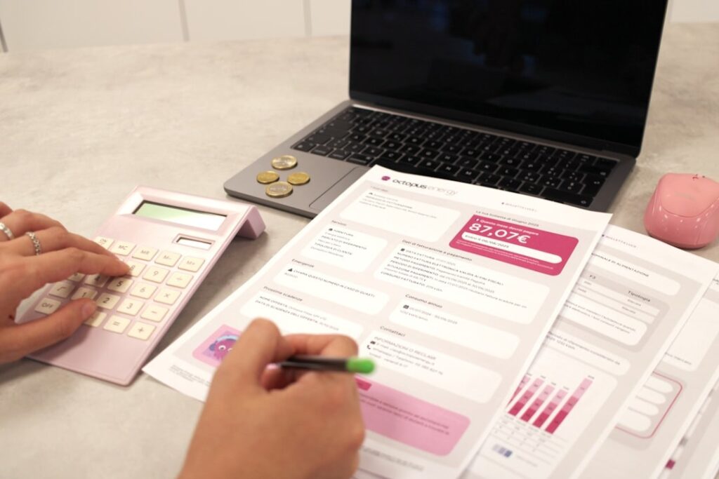 A person at a desk reviewing a moving budget on a laptop next to a calculator and notebook