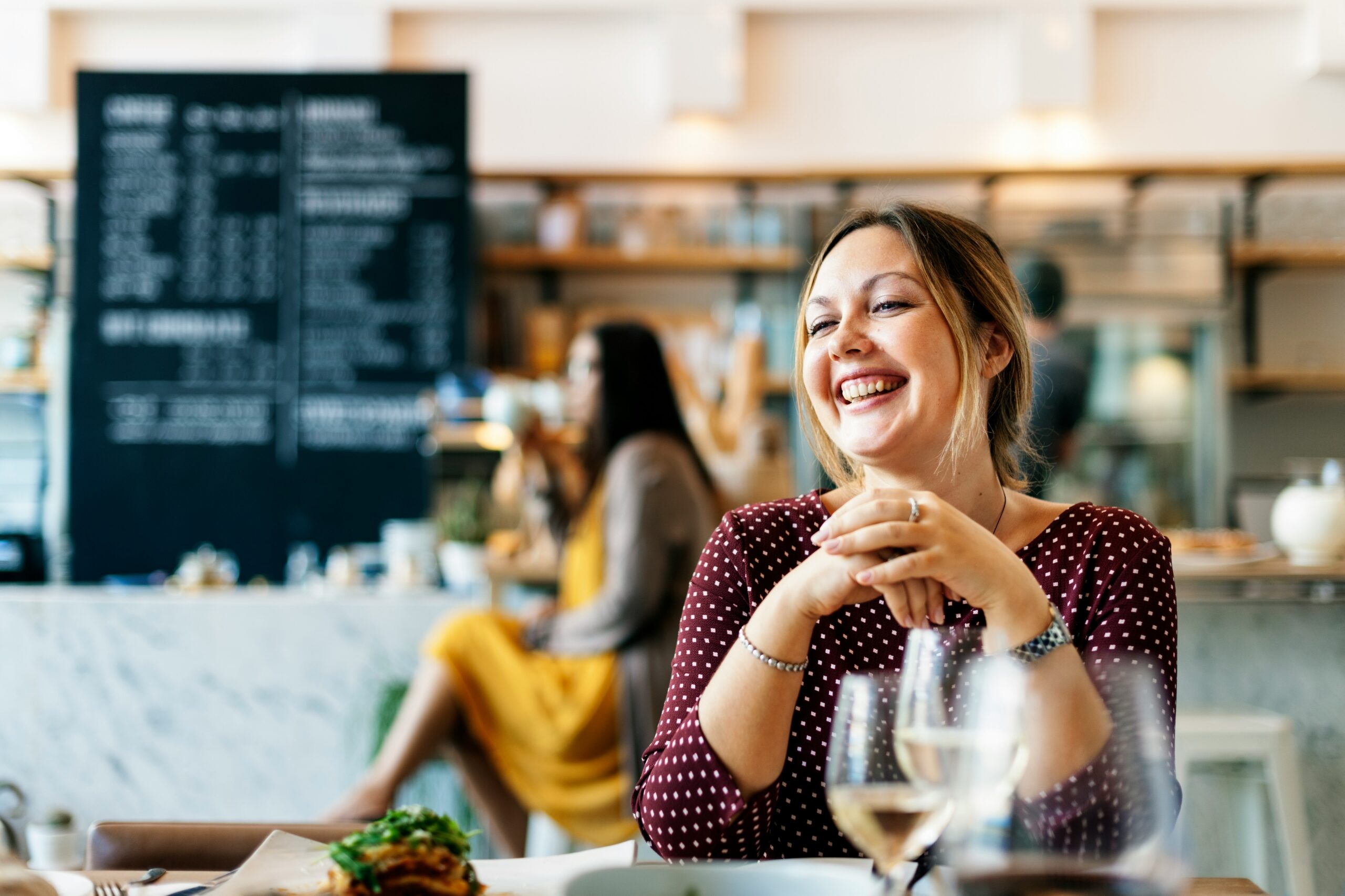 young woman sits in a cafe smiling