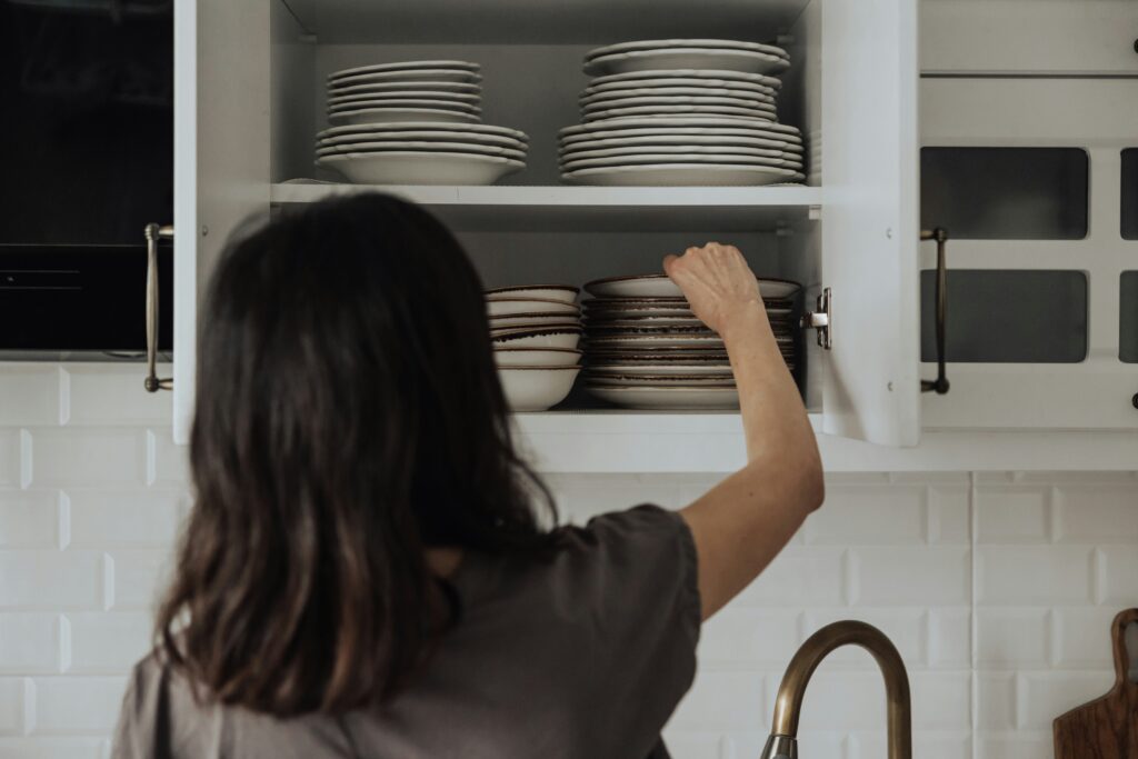 young woman putting clean dishes away
