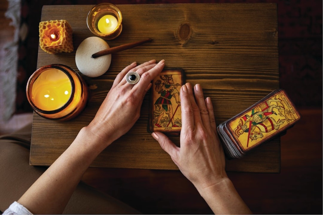 Hands holding a single tarot card over a linen cloth