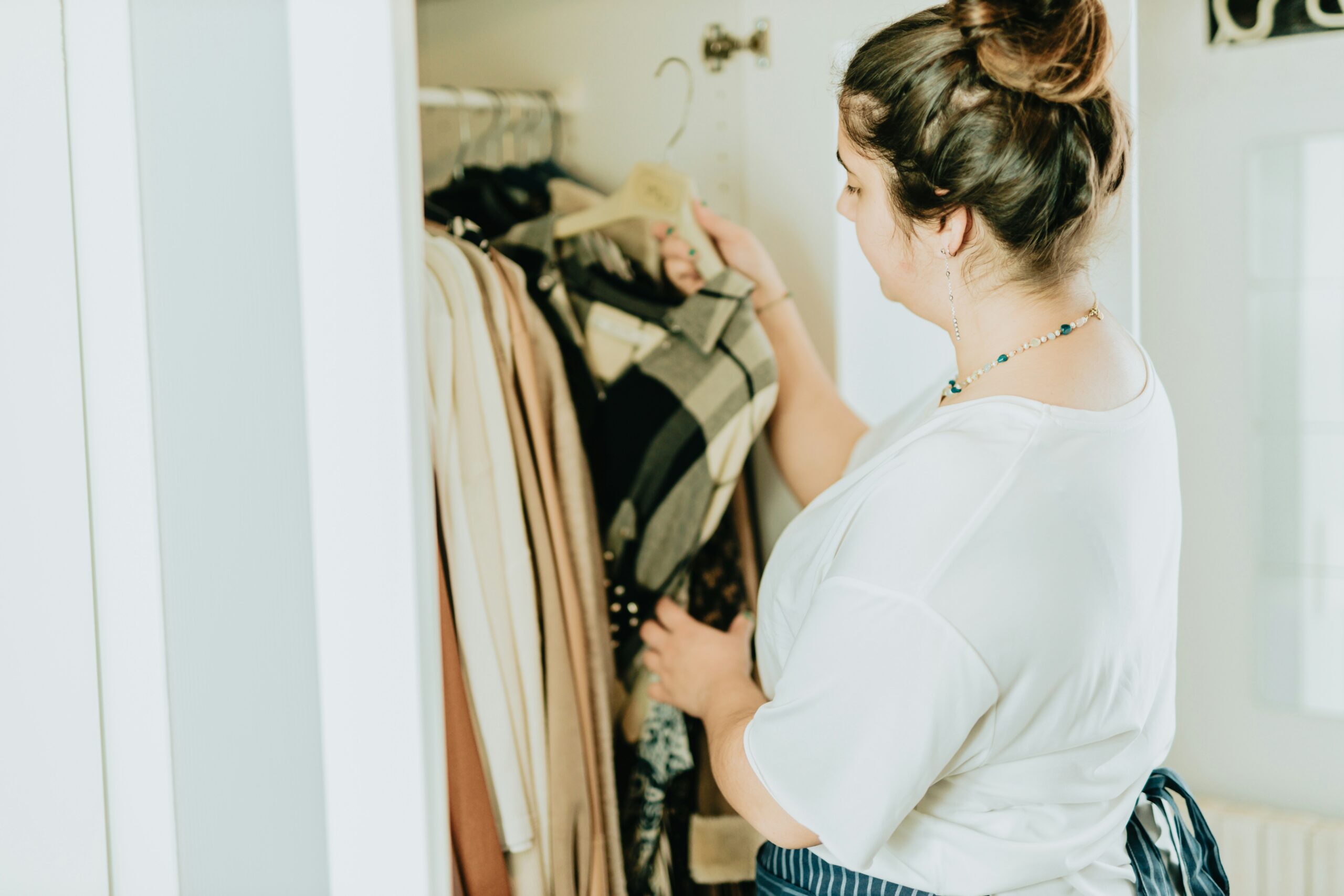 young woman hangs clothing in her closet