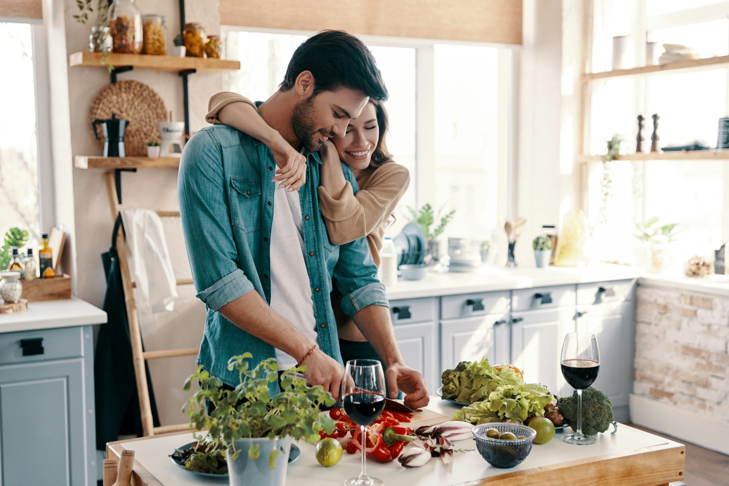 a couple stands together in a kitchen preparing food