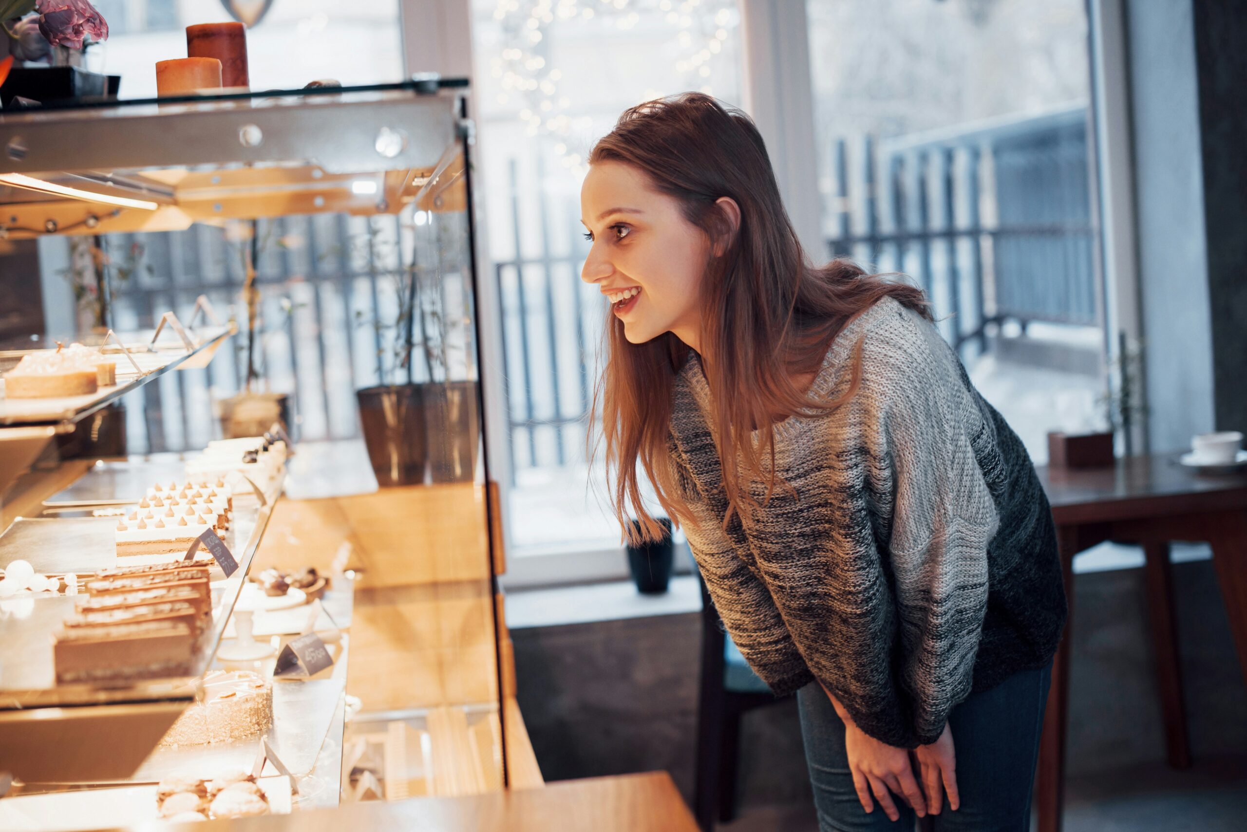 young woman looks at a bakery display case
