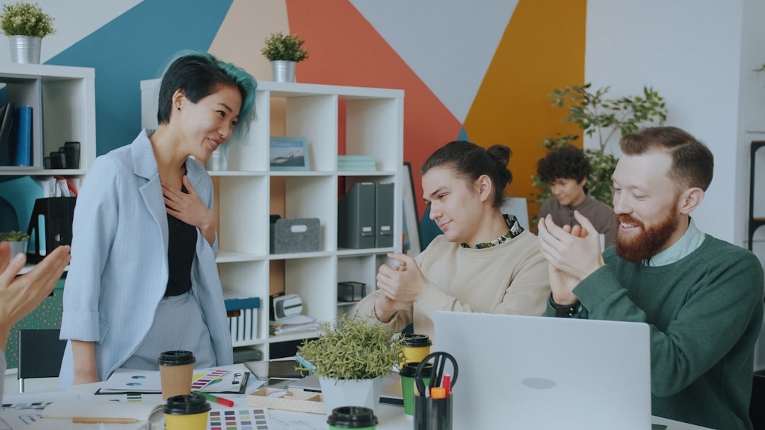 A group of young colleagues applauding a coworker in a bright open plan office